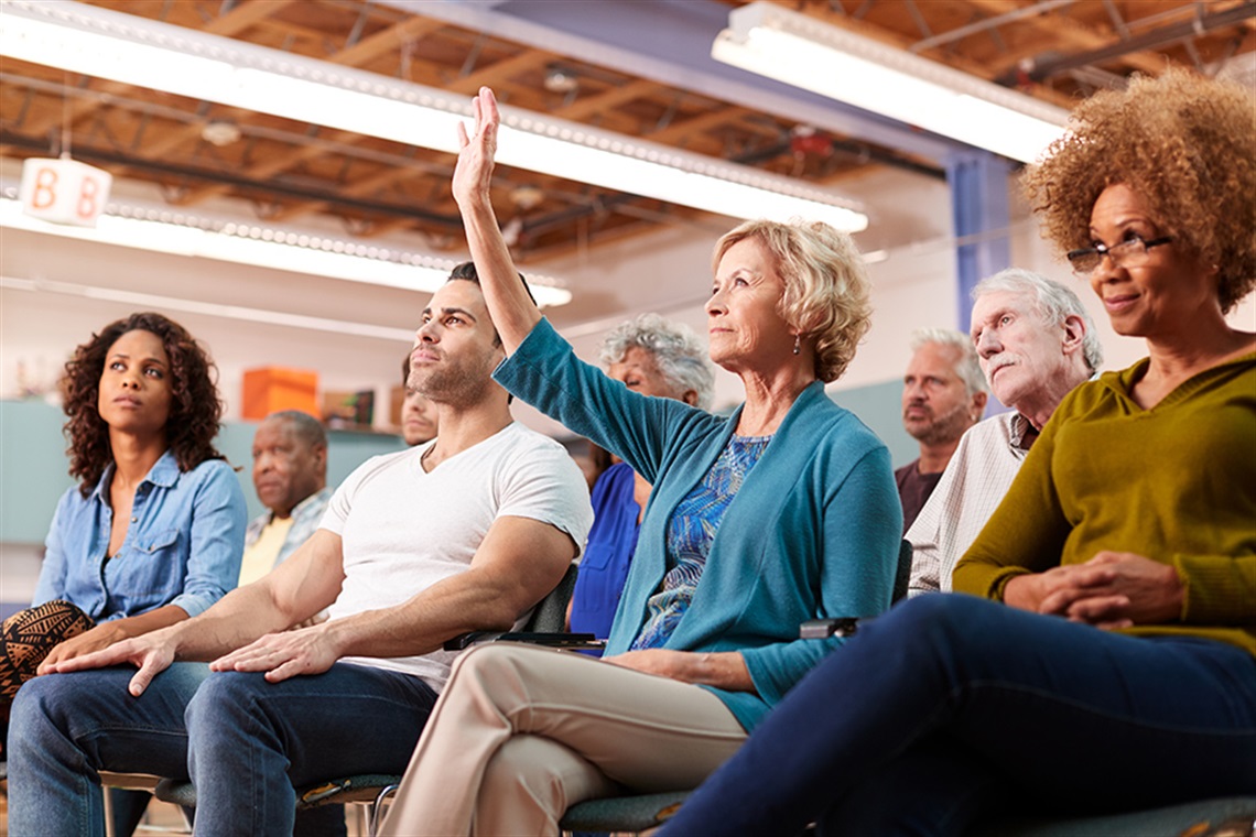 woman raising her hand at a Town Hall meeting