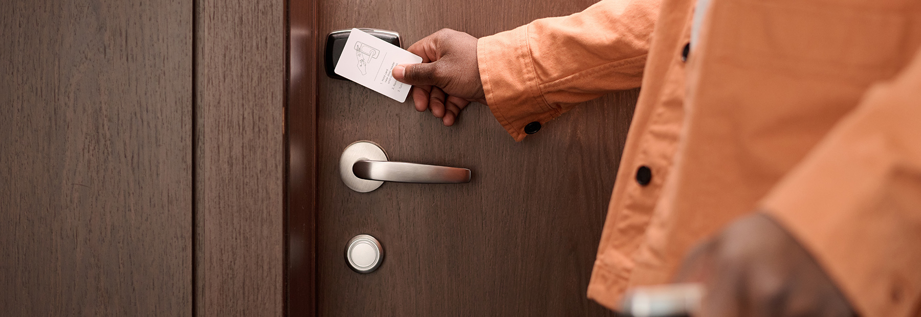 Close up of guest opening hotel room door and pressing keycard on lock.