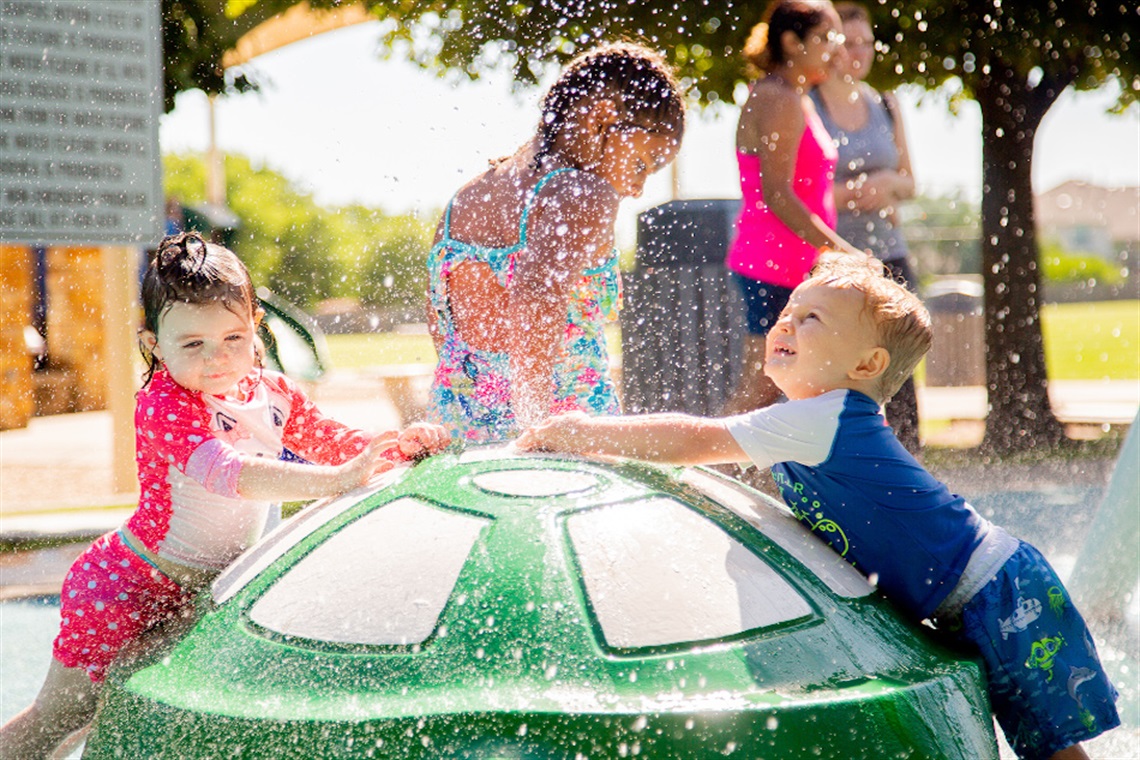 Three young children playing on turtle feature at Don Misenhimer Splash Pad Three young children playing on turtle feature at Don Misenhimer Splash Pad