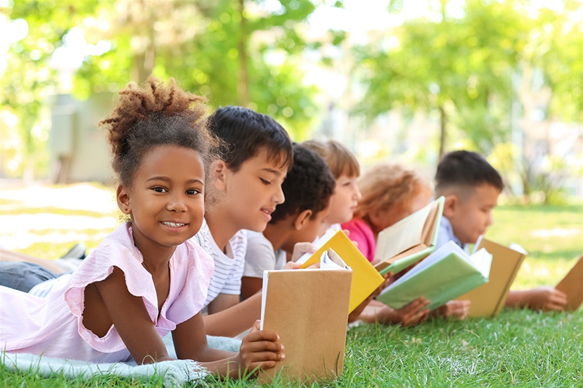 Little children reading books in park.