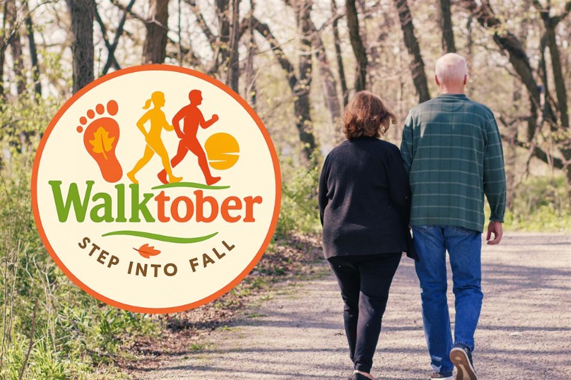 A couple walking along a wooded trail with an event logo that reads Walktober: Step into Fall
