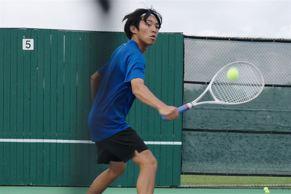 Wesley Bui volleys tennis ball near the net.
