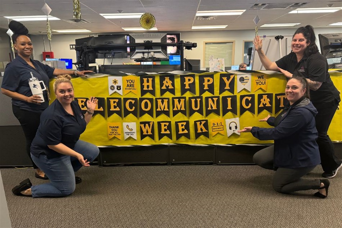 Arlington Dispatch employees with banner that reads Happy Telecommunicators Week