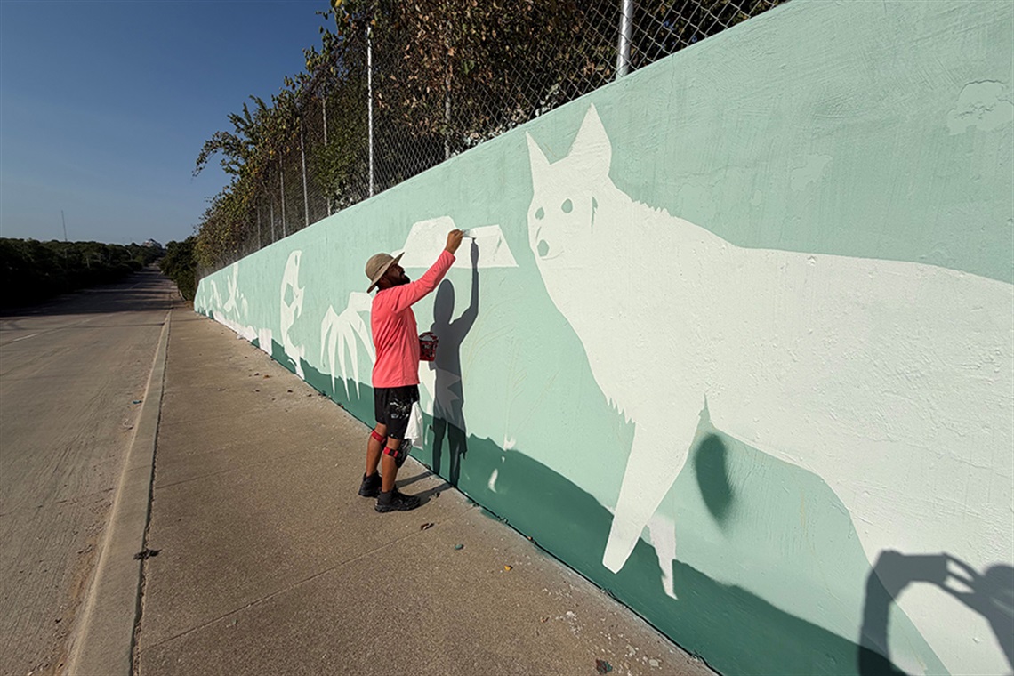 Man painting a mural with wild animals on it