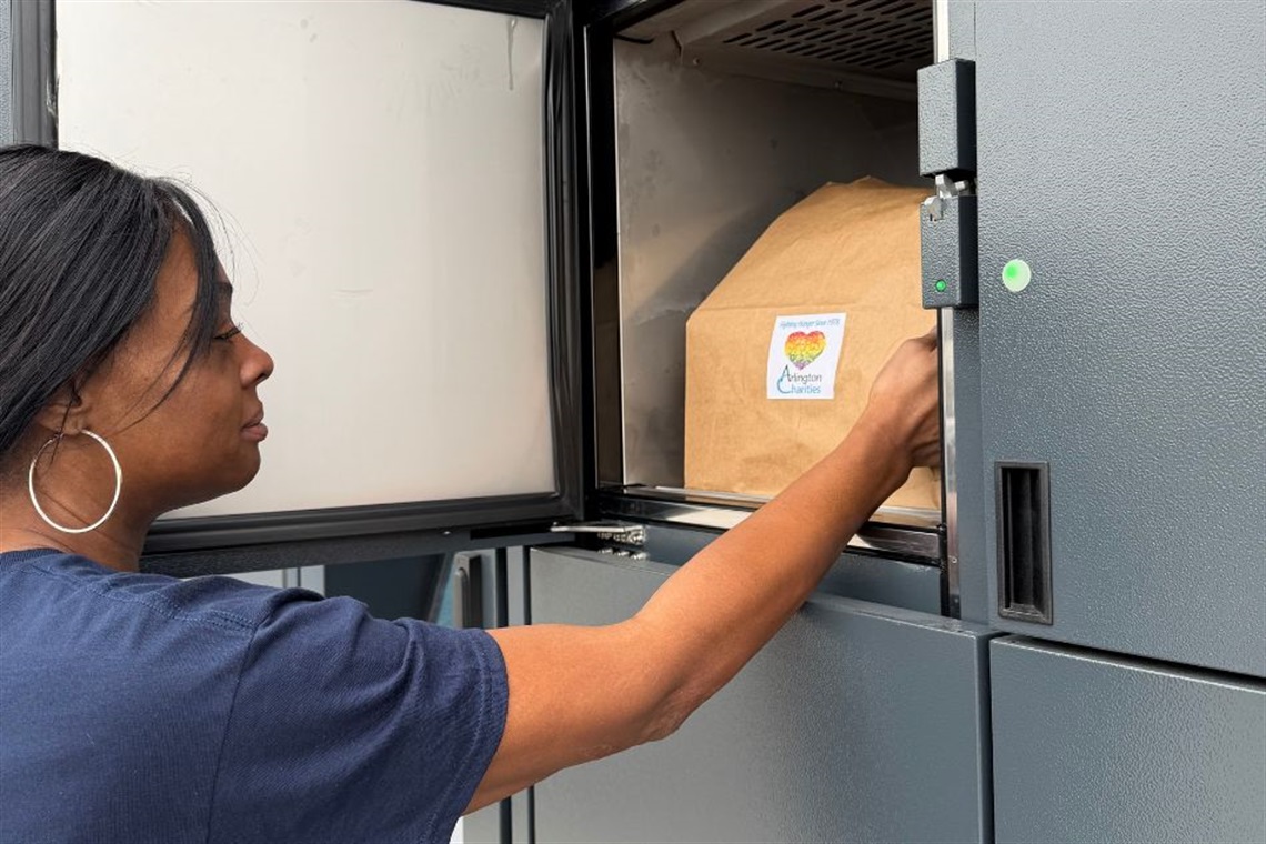 A client accessing a bag of groceries from an Arlington Charities locker.