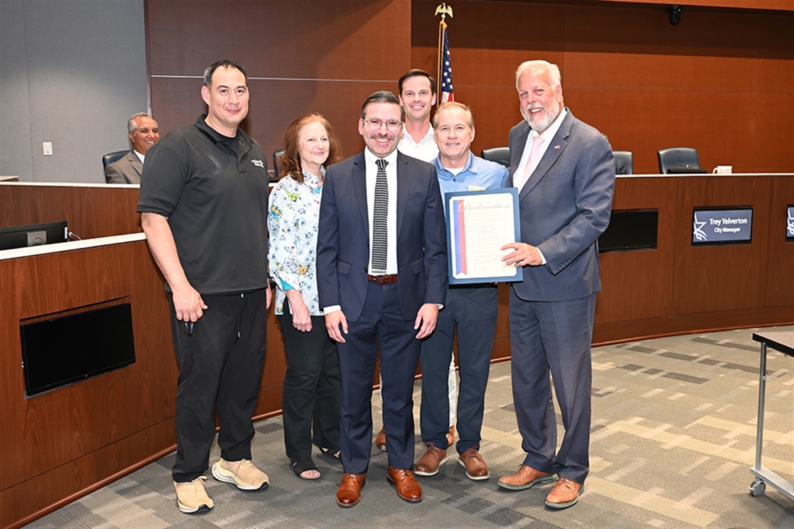 People smiling for camera while Mayor Jim Ross holds proclamation.