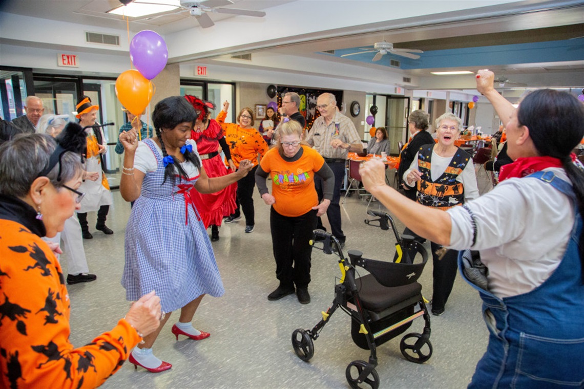 Group of seniors in costumes dancing at halloween party