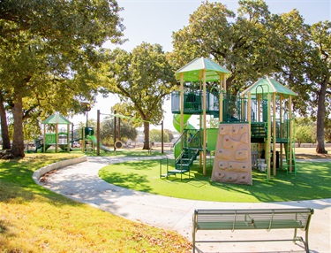 Playground, bench, and paved walking path at High Oak Park
