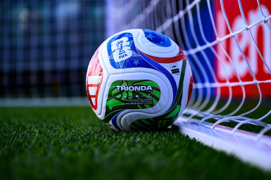 Official FIFA World Cup soccer ball positioned near a goal line on a grass field.