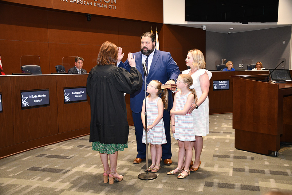 Man with woman and children being sworn in as council member