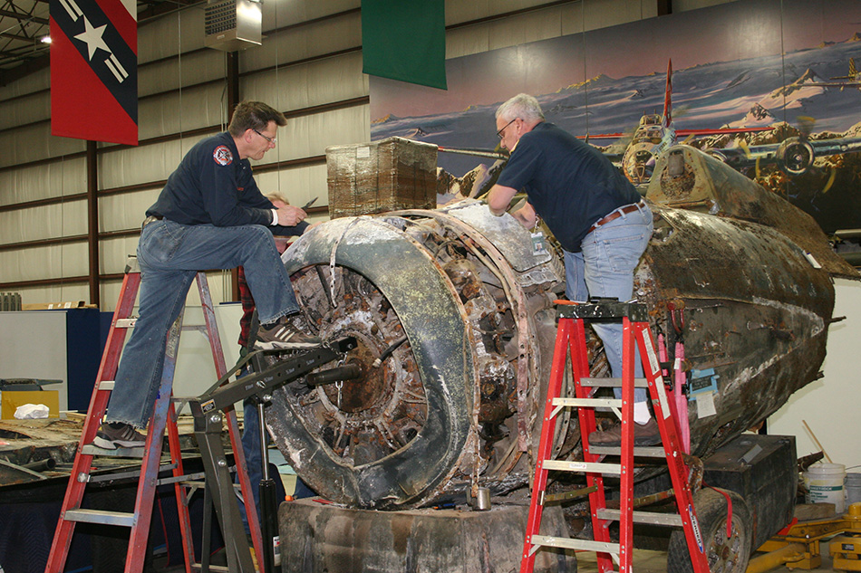 Two Men on ladders looking at recovered aircraft part