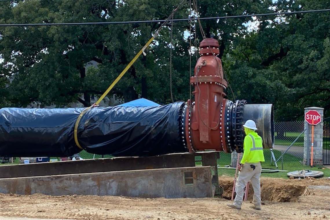 Public Works Department employee surveying large outdoor pipe 