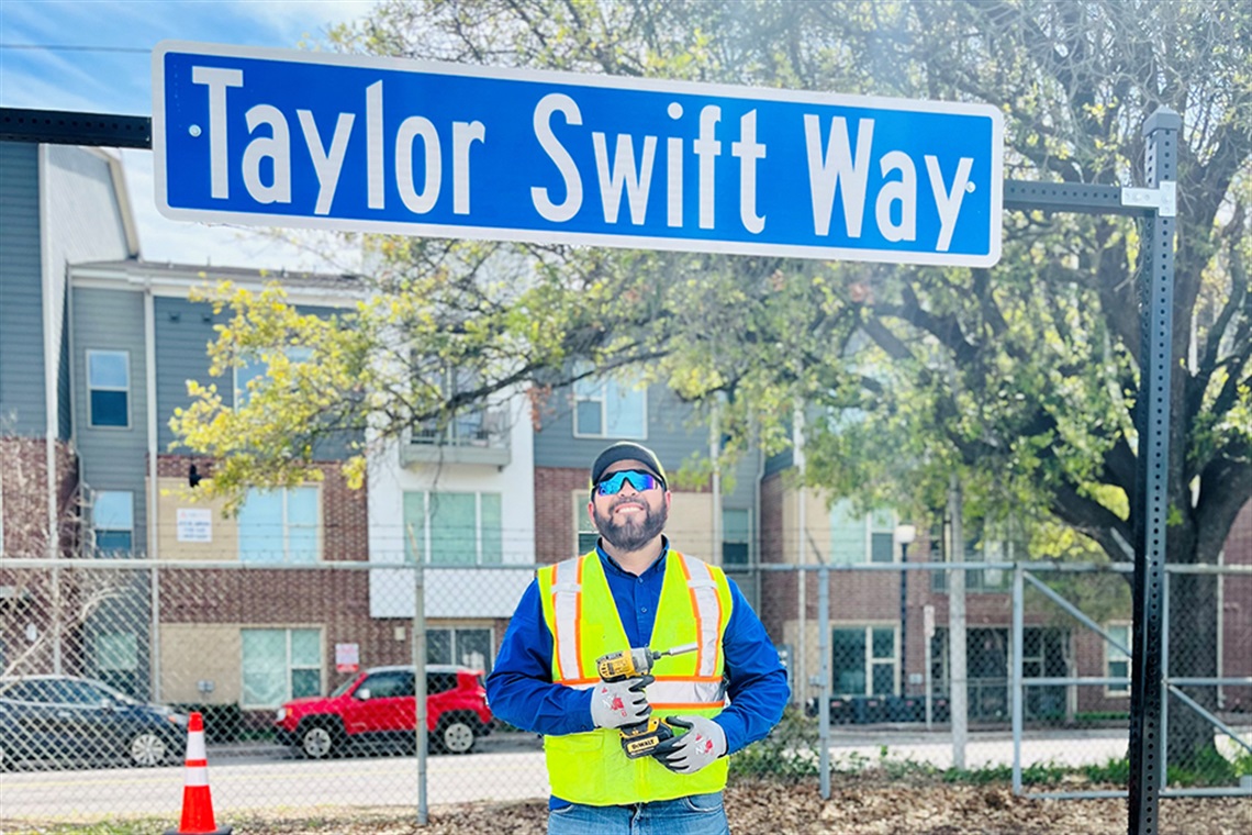 Public Works employee poses for picture after the completed installation of Taylor Swift Way sign.