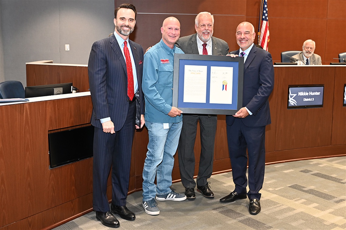 City and state leaders pose for photo displaying proclamation celebrating Arlington's sesquicentennial. From left to right: Jay Warren, Tony Tinderholt, Jim Ross, and Chris Turner. 