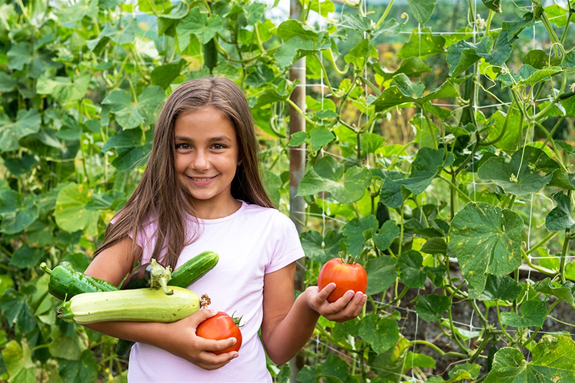 Young Girl Holding Fresh Vegetables from a garden