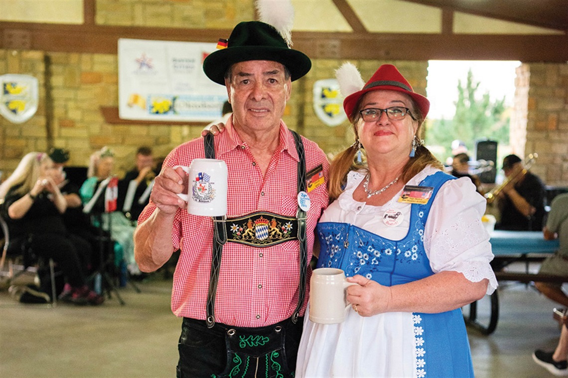 Photo of a man and woman in German attire holding beer steins at the City of Arlington's Oktoberfest.
