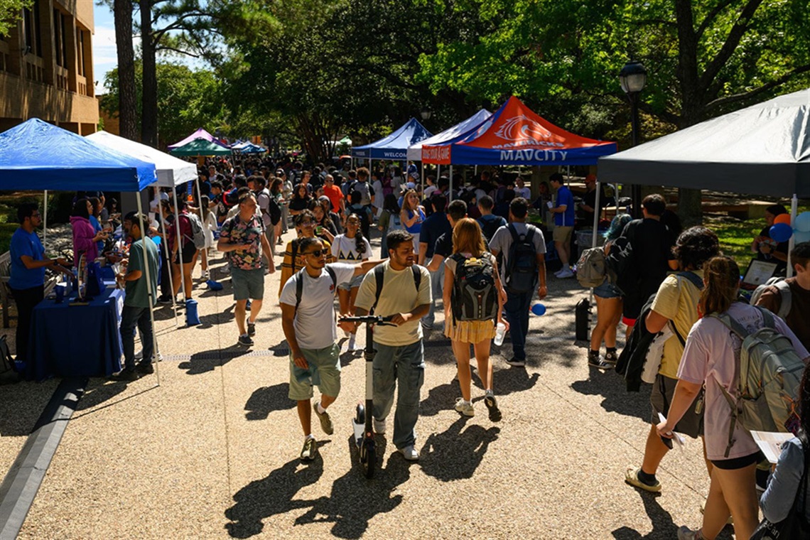 Photo shows dozens of college students walking outside on the sidewalk at the University of Texas at Arlington