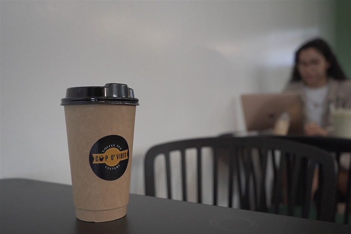 Cup O' Vibes drink container with logo sitting on table. 