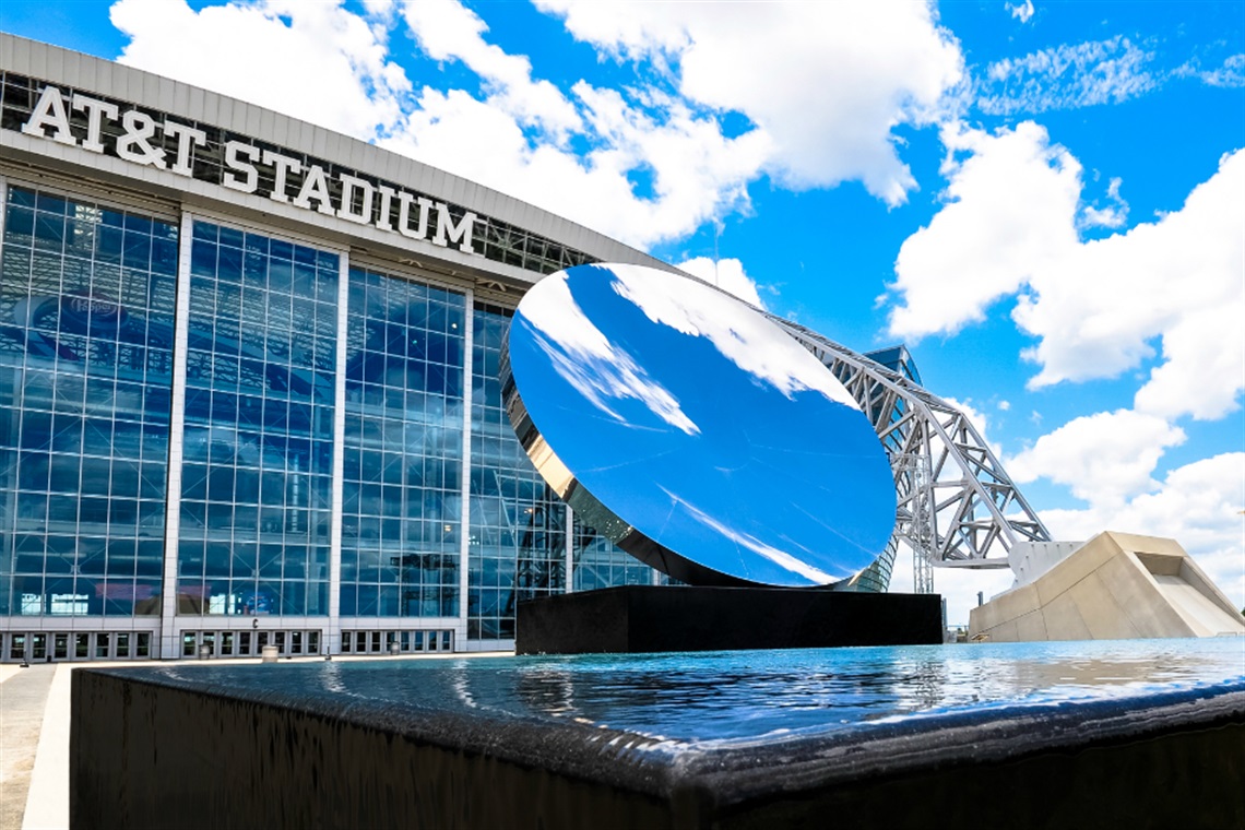 Exterior photo of AT&T Stadium with reflective mirror out front.